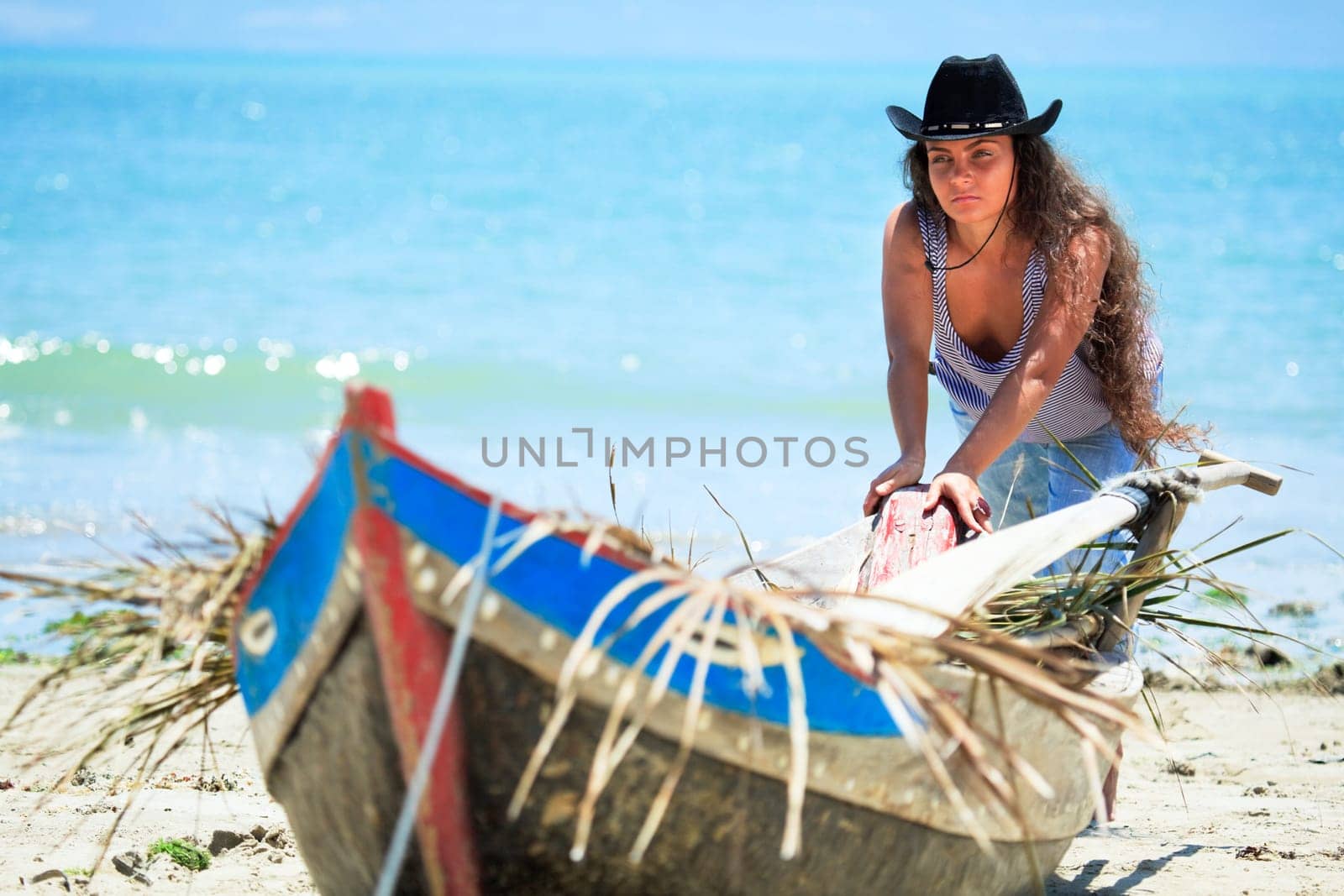 Young beautiful fisherwoman with boat on the beach
