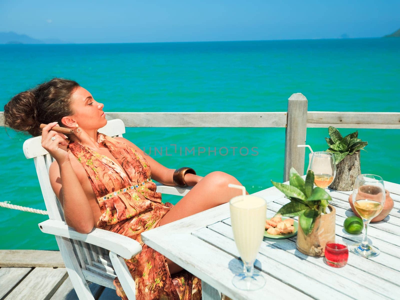 Young woman with cigar have a dinner on the beach