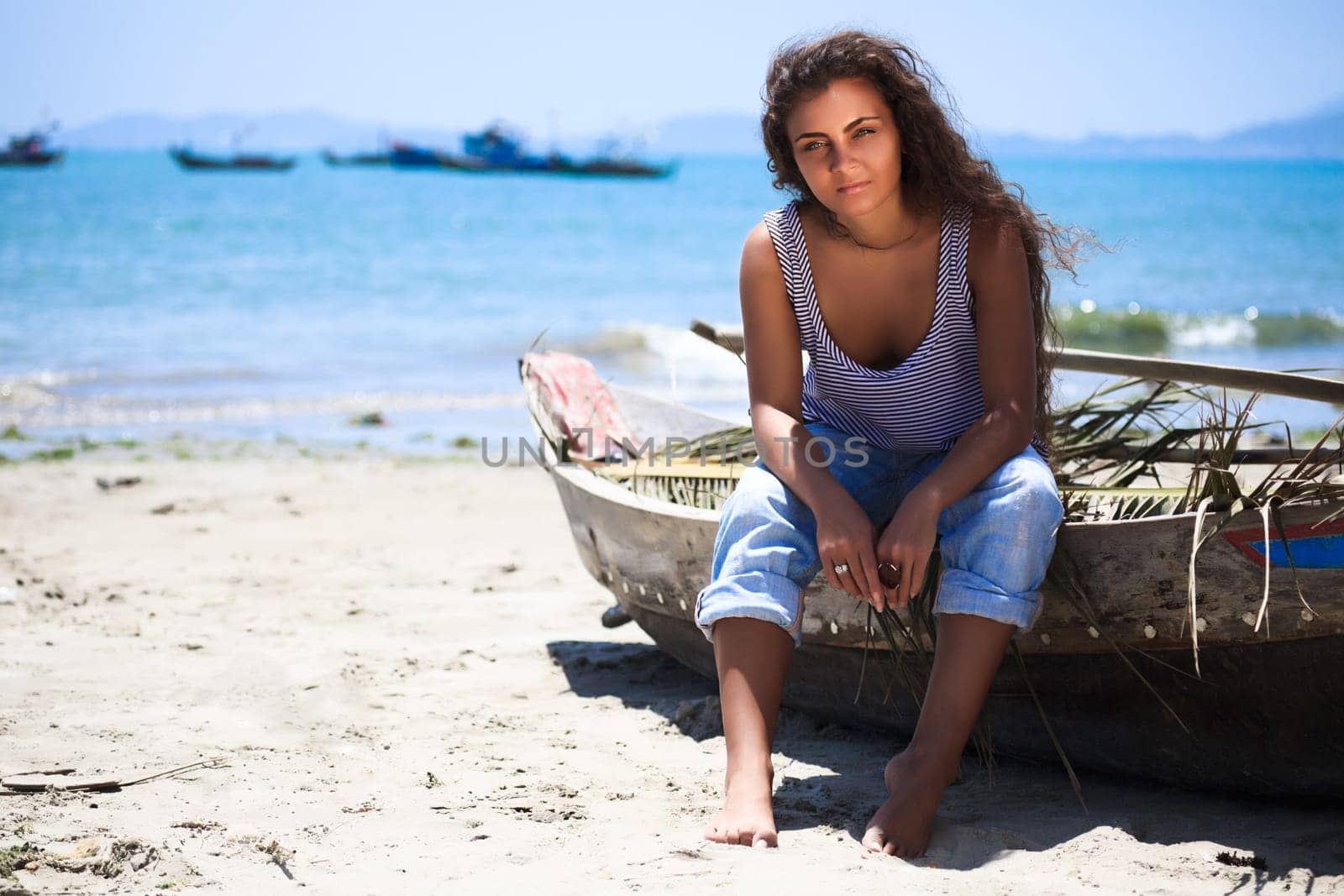 Young beautiful fisherwoman with boat on the beach