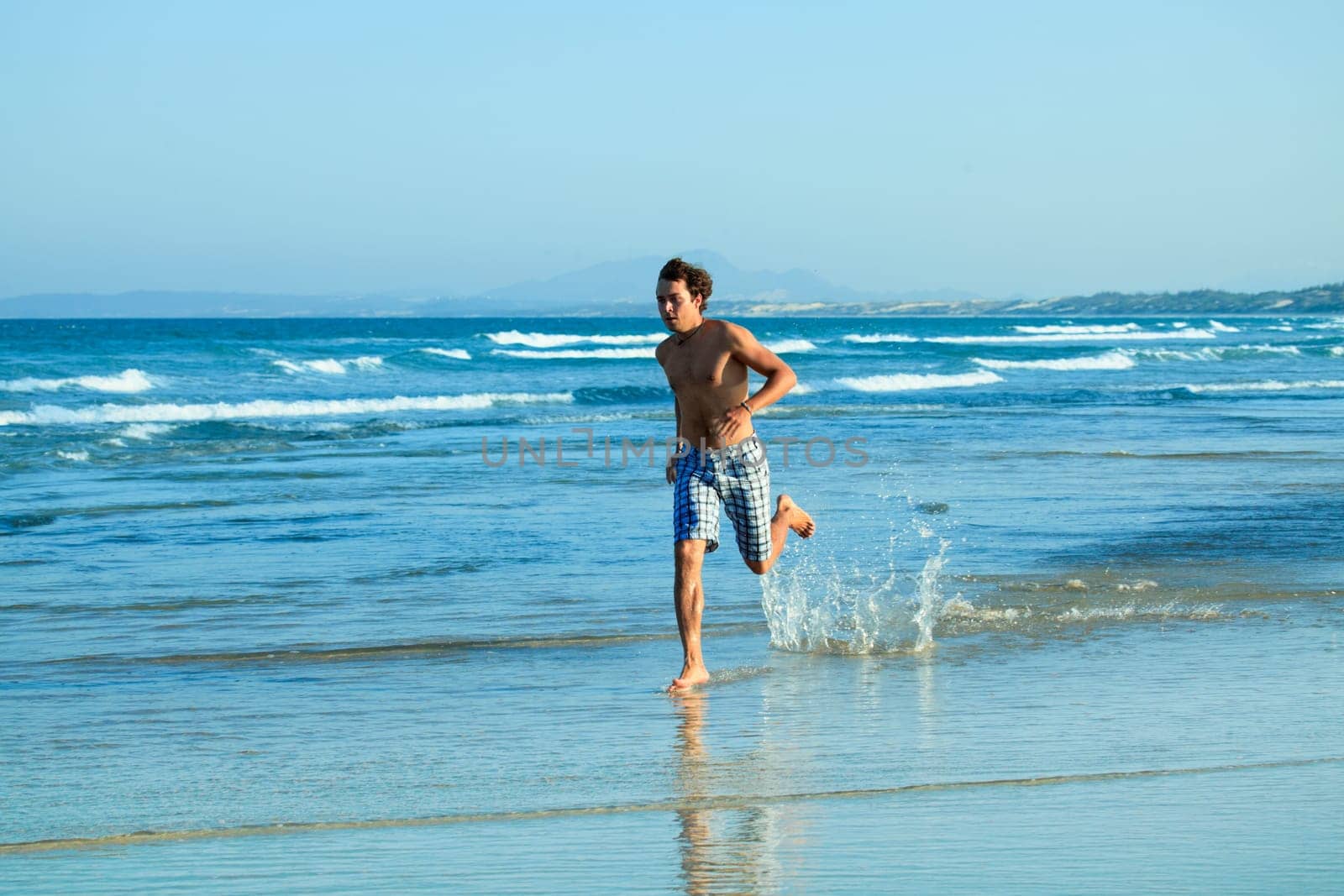 Young handsome man  running on the beach