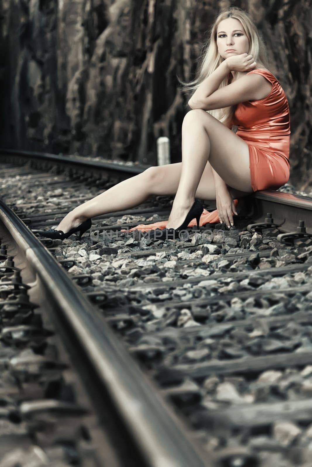 Young beautiful woman sitting on train track