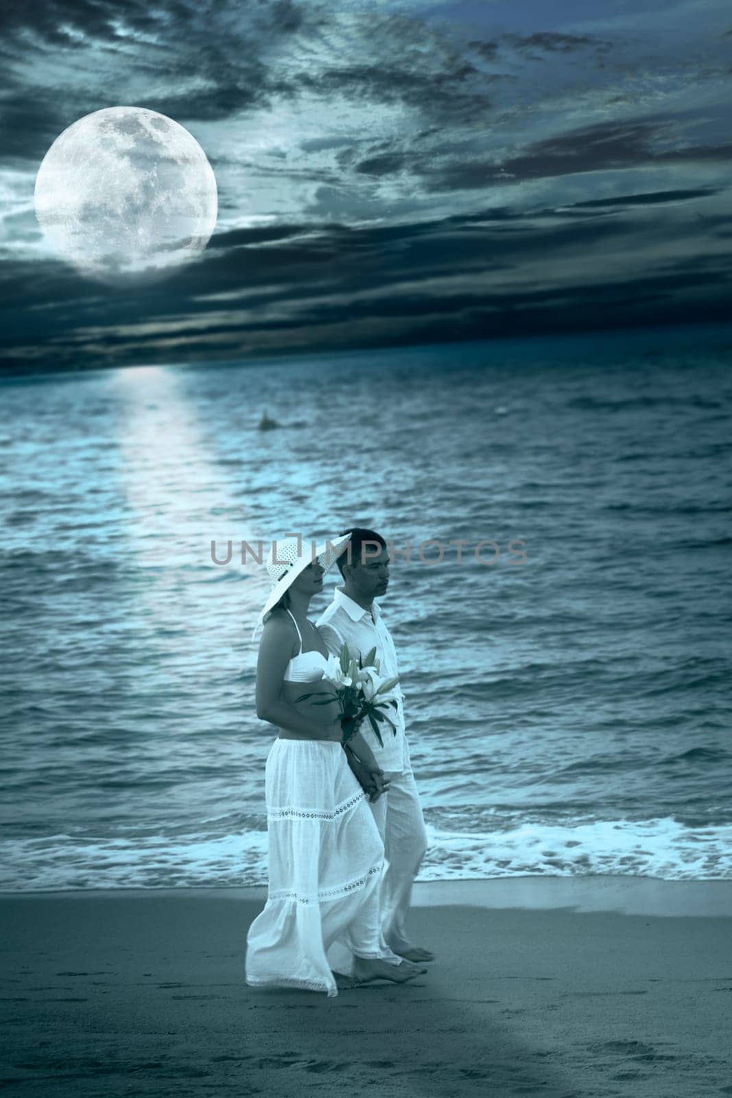 Romantic couple walking near ocean at night time