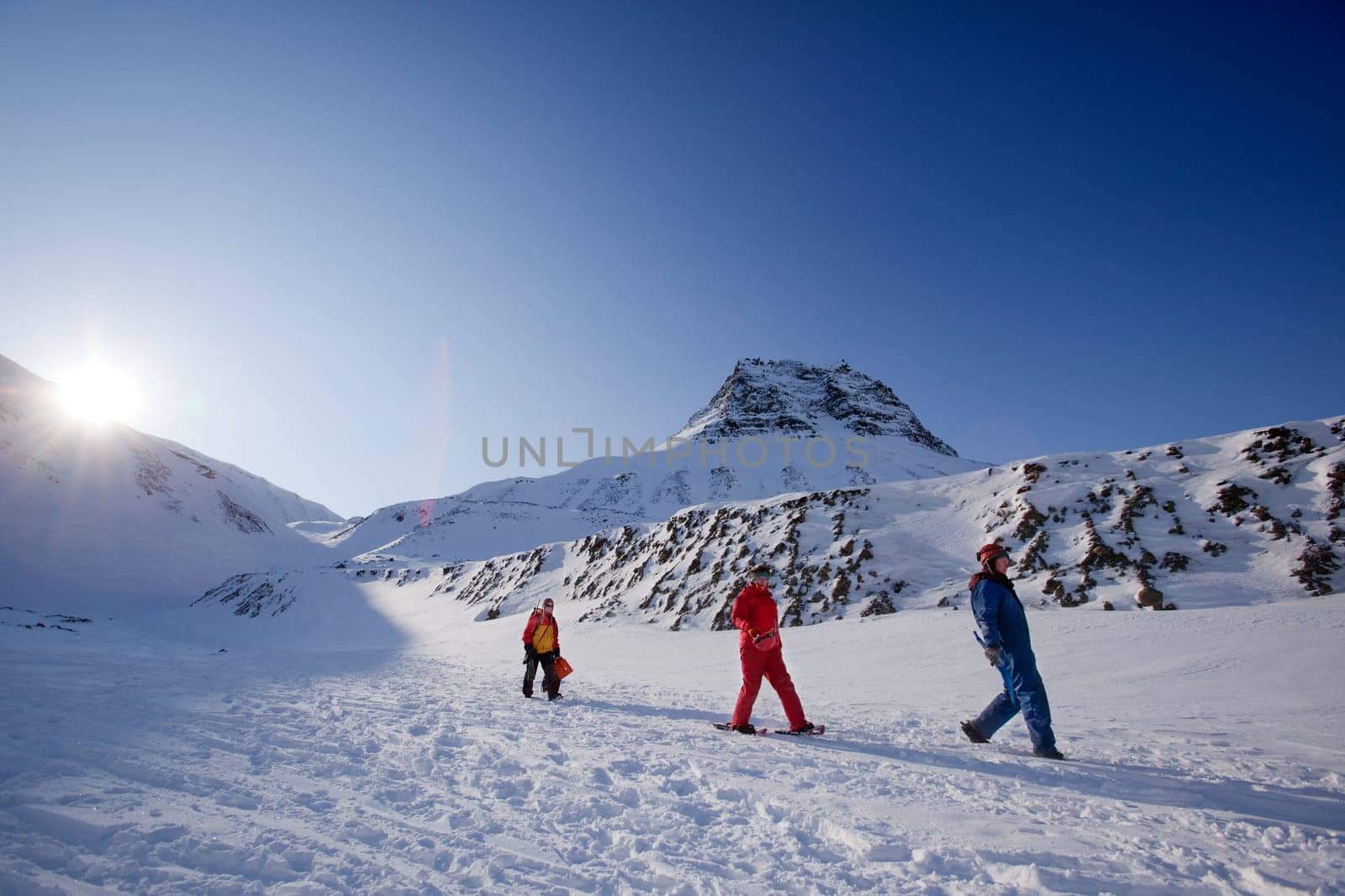 Three people on a short mountain trek, against a beautiful winter landscape