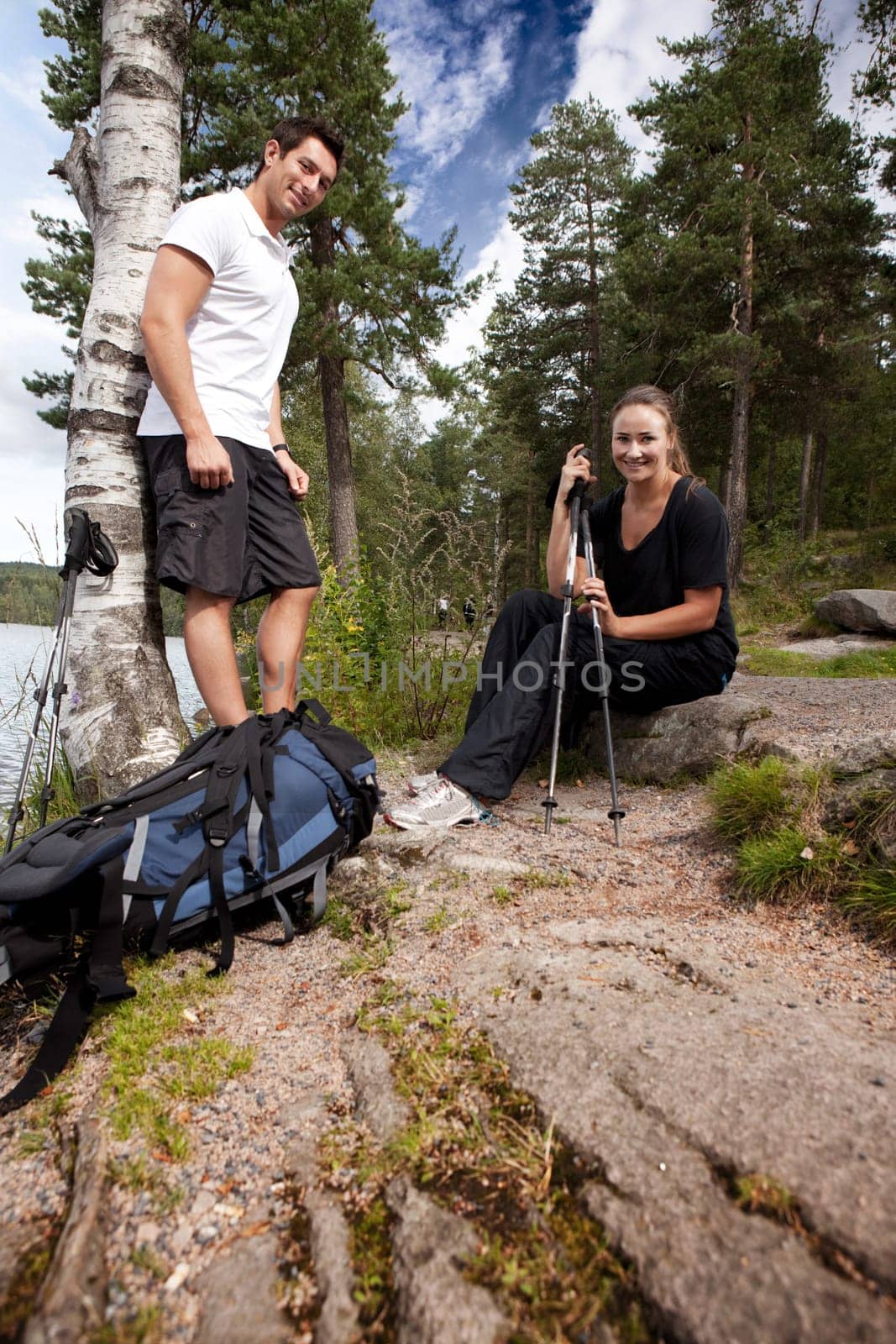 A couple hiking in the woods taking a break by the lake