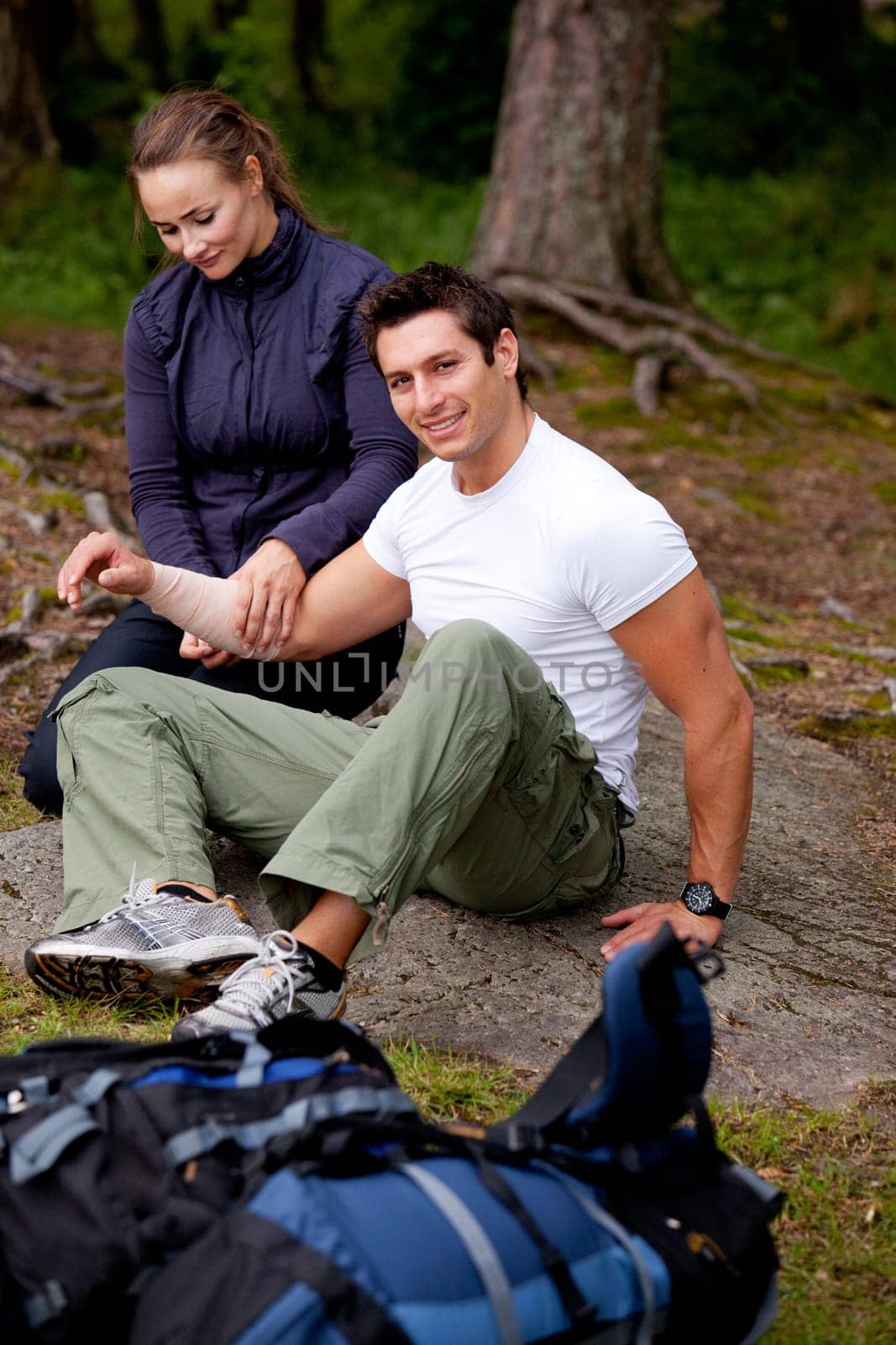 A woman applying an arm bandage on a male camper - focus on male face