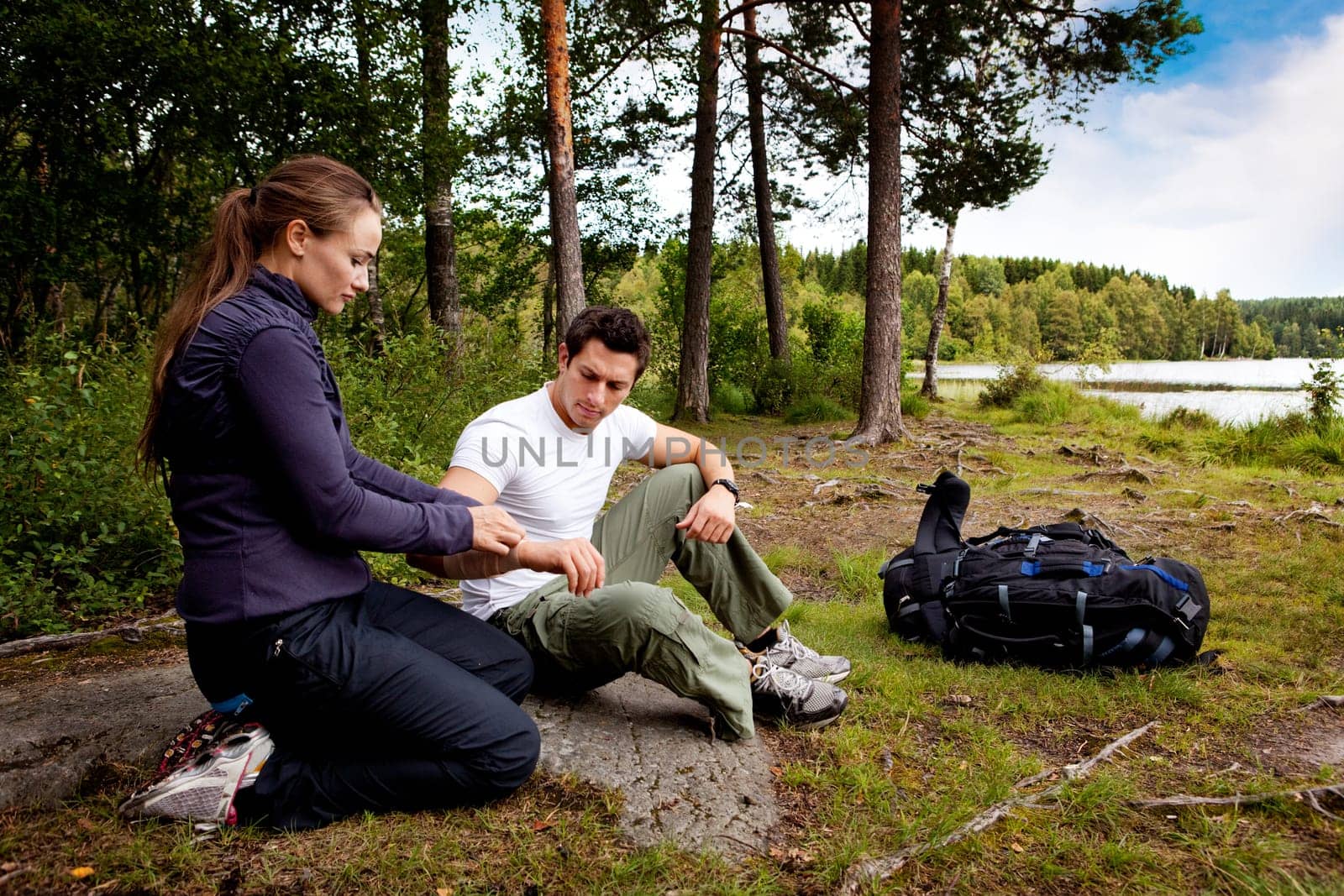 A woman applying an arm bandage on a male camper