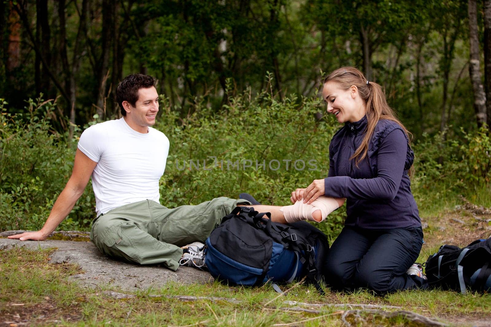 A couple camping and putting on a leg bandage