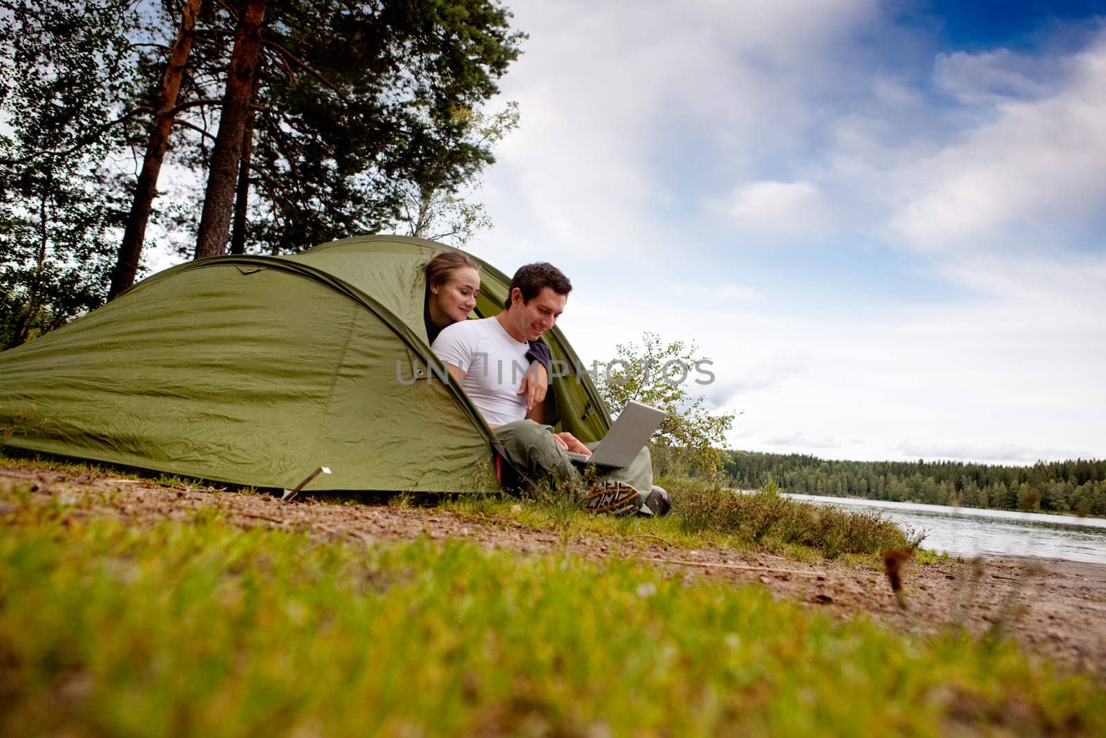 A man and woman using a computer outdoors in a tent