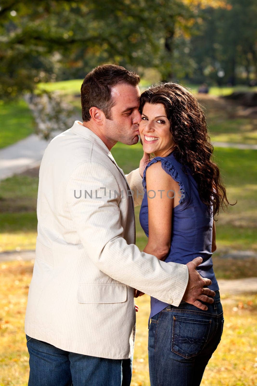 A couple kissing with the woman looking at the camera