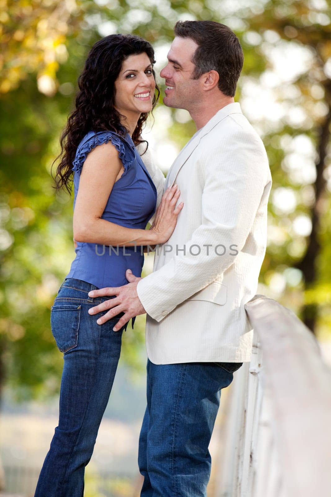 A couple in the park with the man smiling at the woman