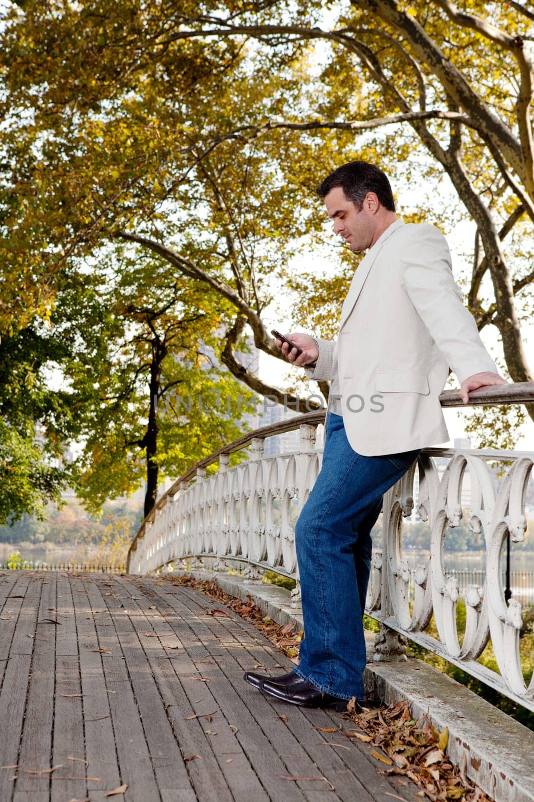 A man checking his cell phone in a park