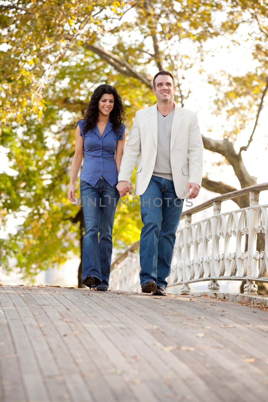 A couple walking on a bridge in a park