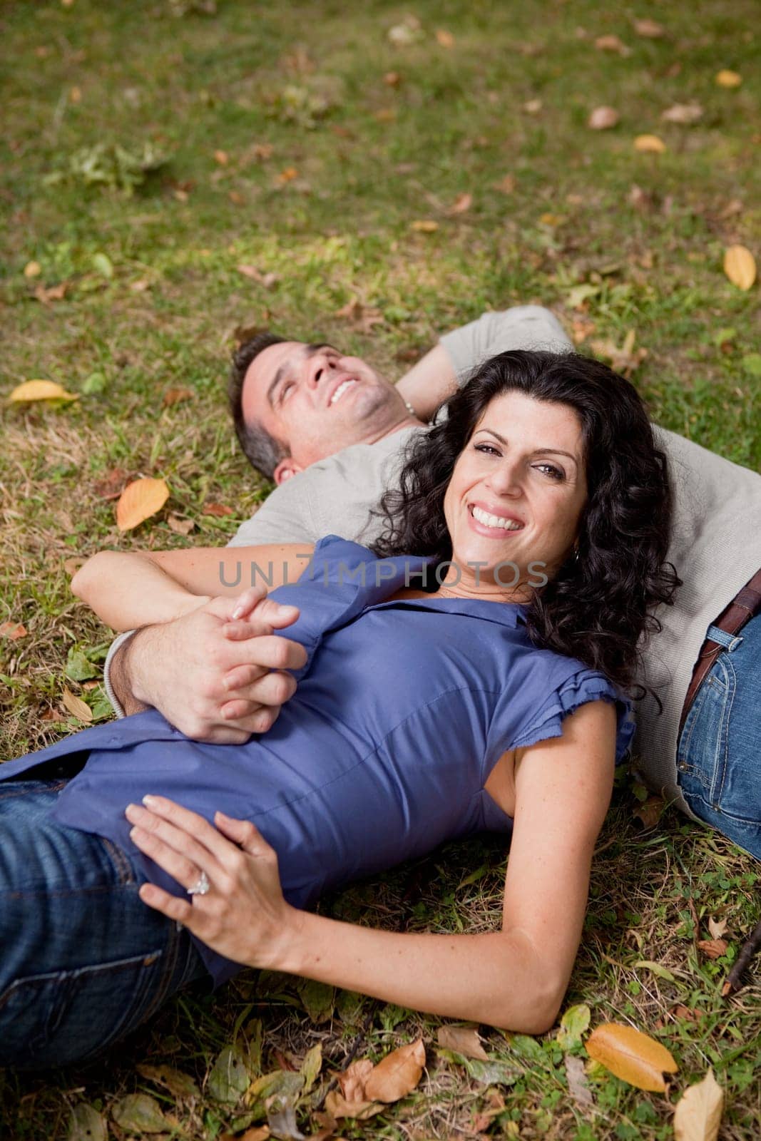 A happy couple relxing laying in the grass - sharp focus on the woman