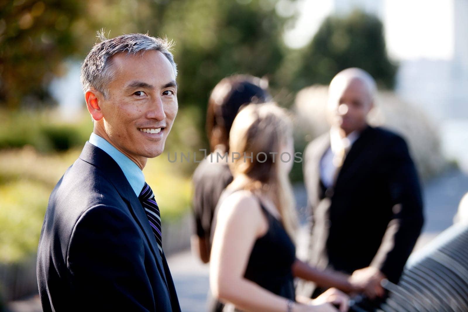 Group of four people with one man as focus. Horizontally framed shot.
