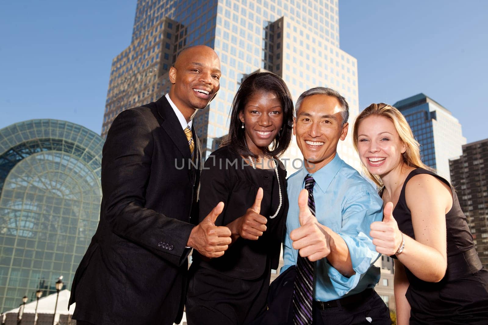Four business people giving thumbs up. Horizontally framed shot.