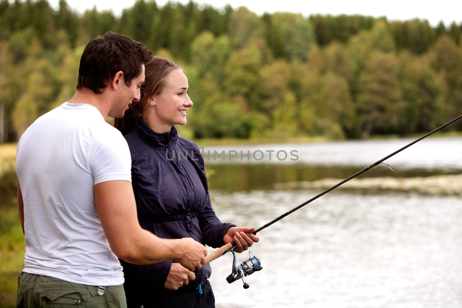 A man showing a woman how to fish