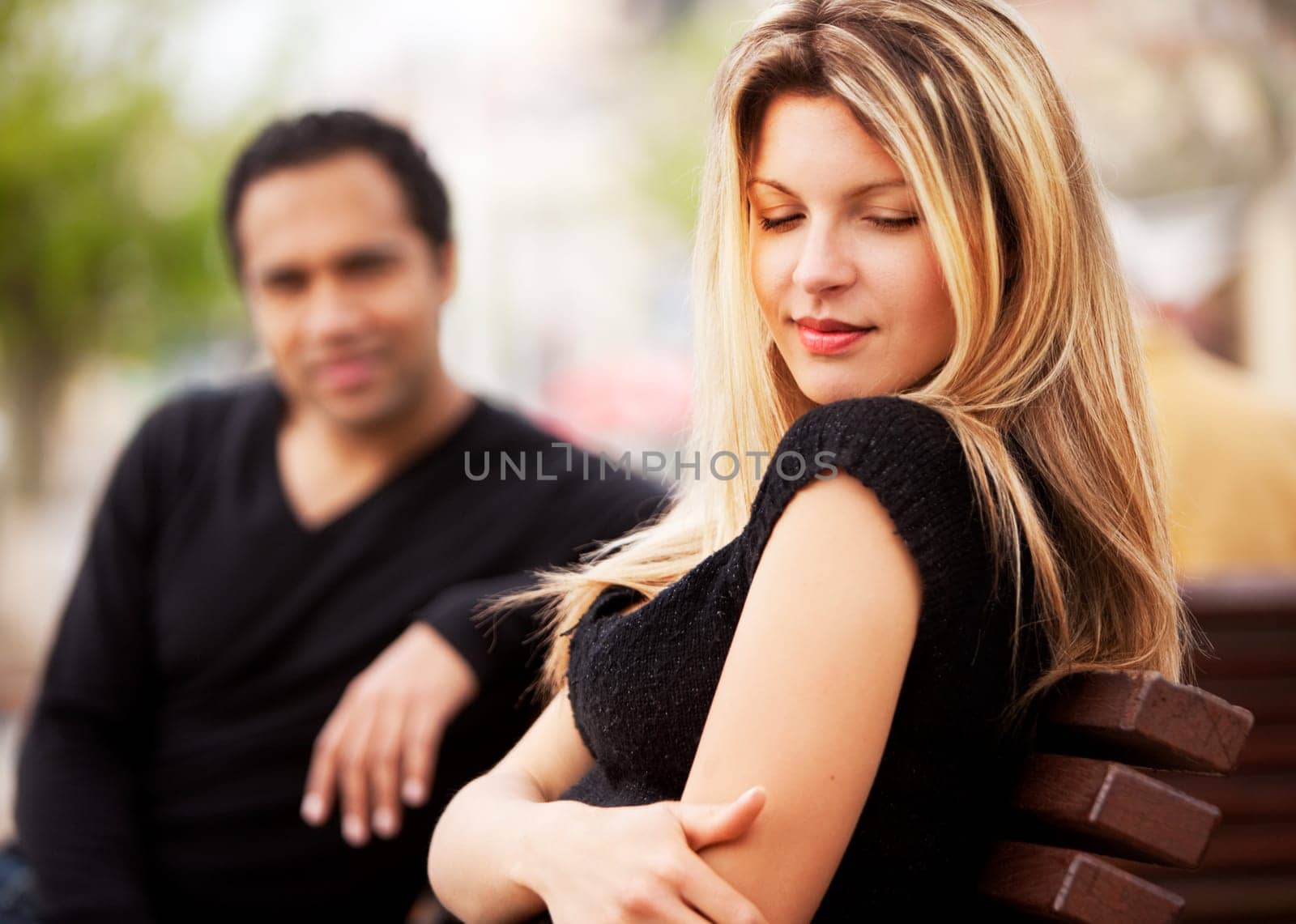 A man and woman sitting on a bench, the woman looking sky