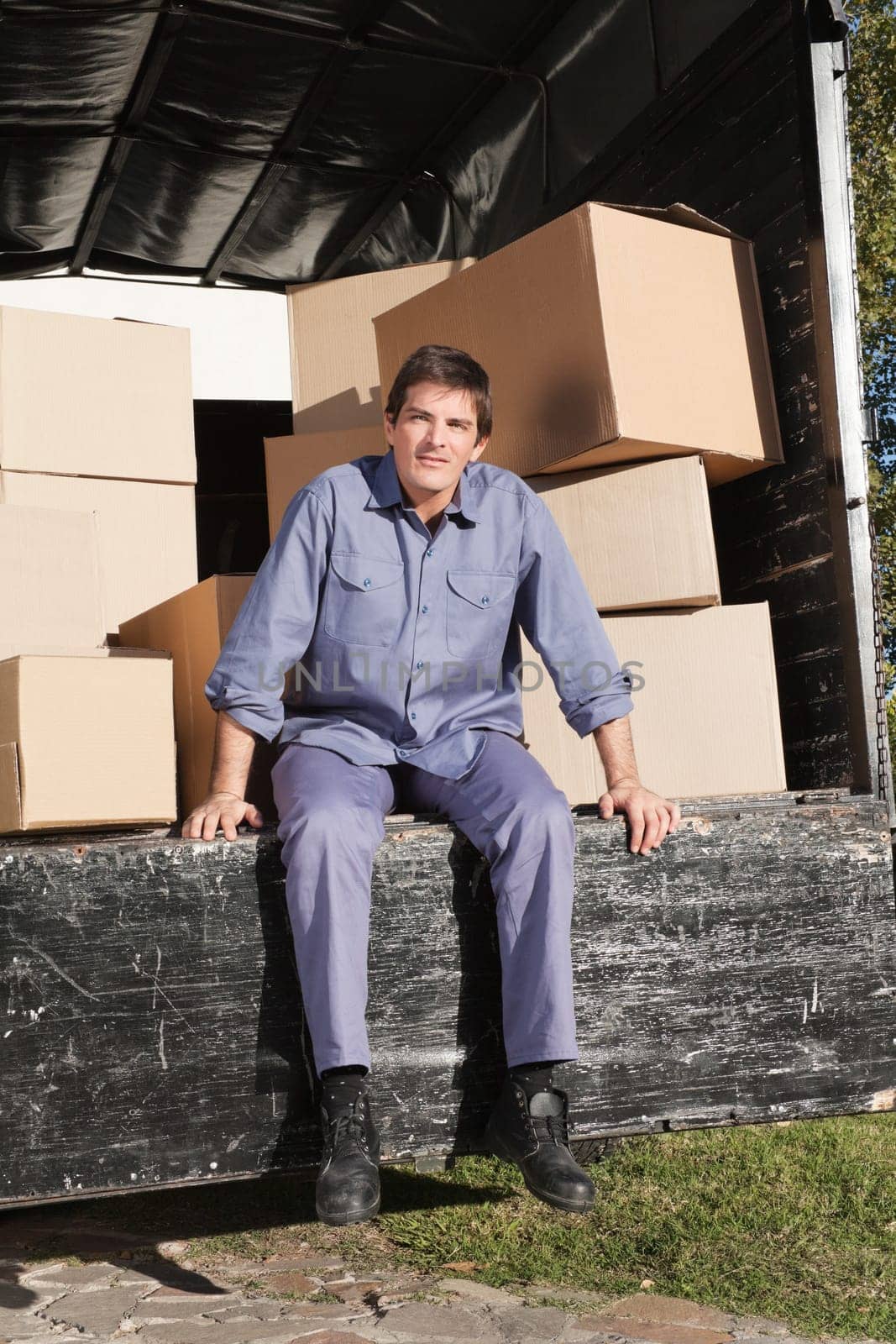 Thoughtful man sitting in the truck with pile of boxes behind him