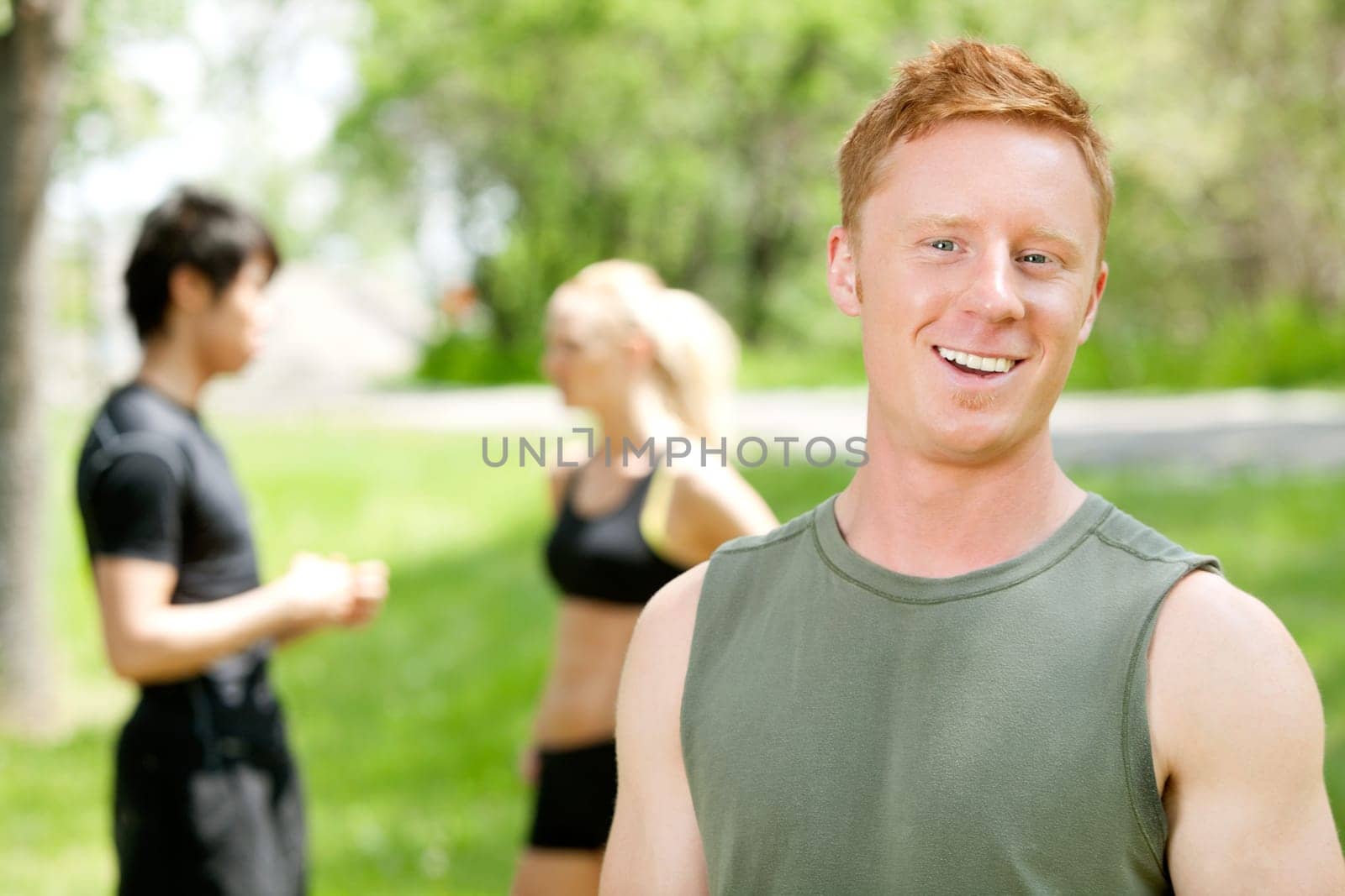 Man smiling and looking at camera while friends talking in the background
