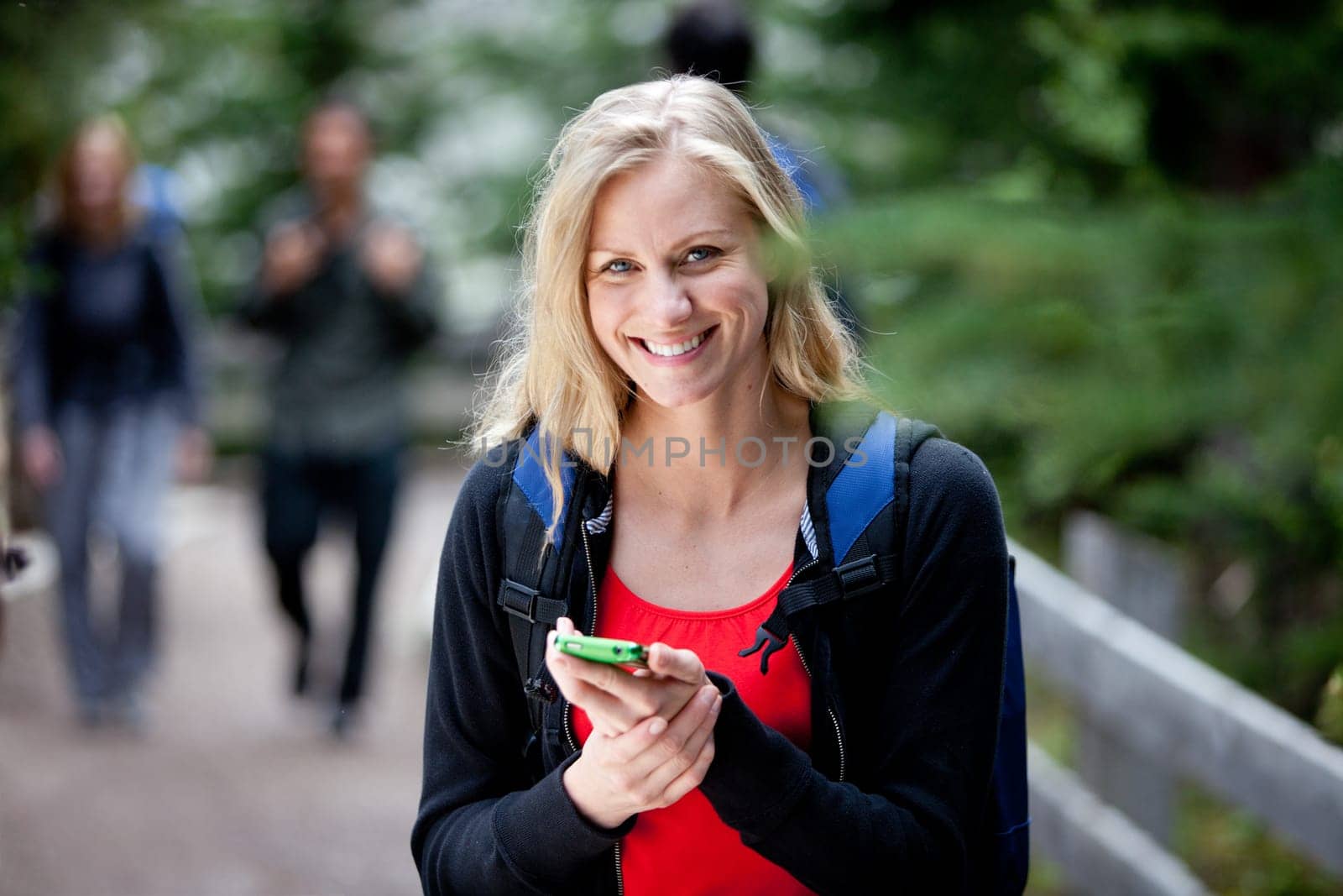 A happy woman holding a smart phone, looking at the camera