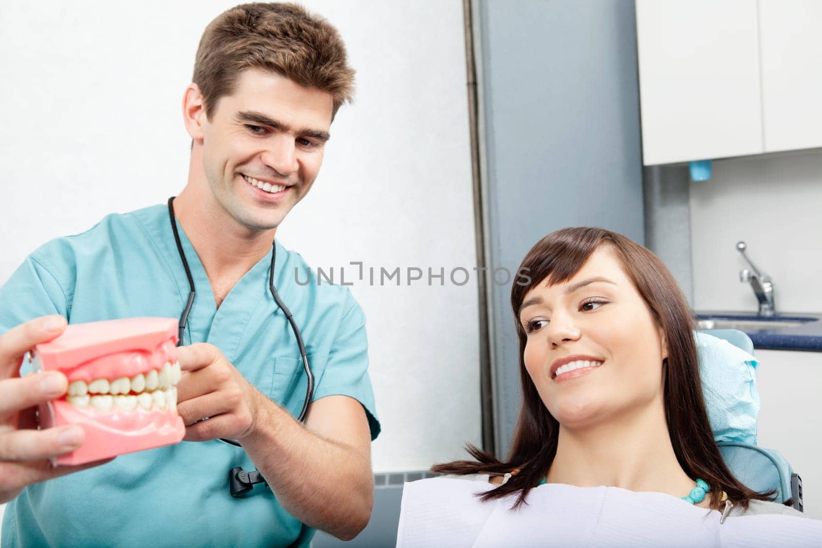 Male dentist explaining a female patient denture work in dental clinic