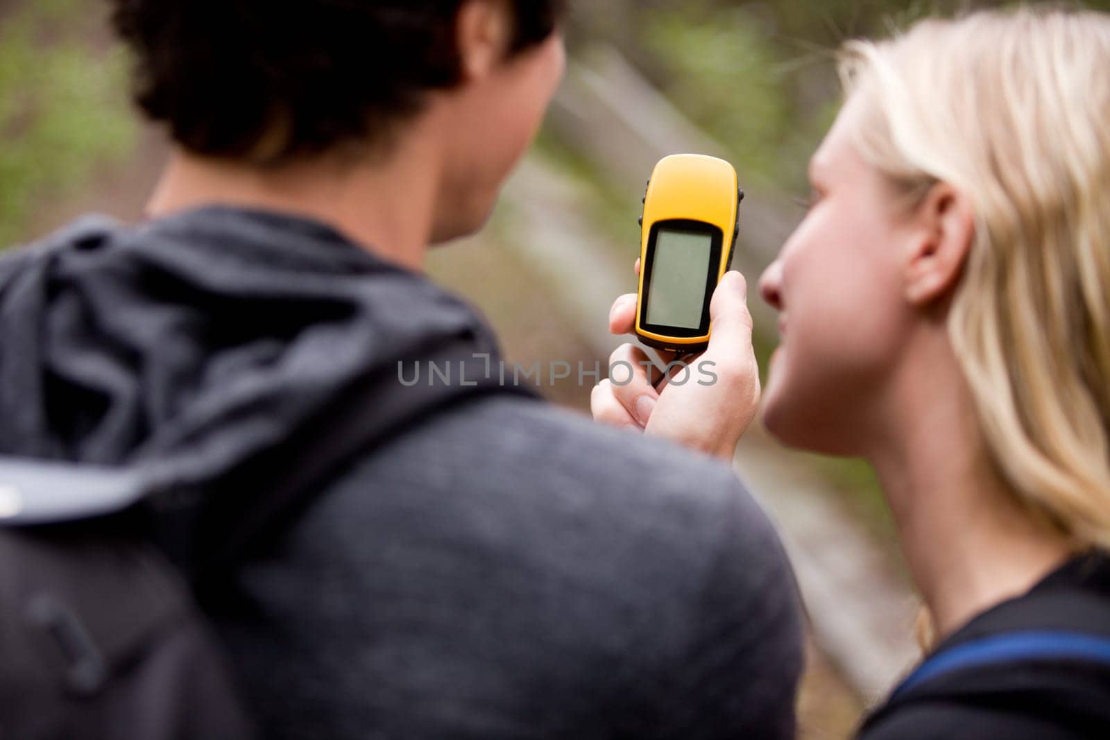 A couple outdoors in the forest using a GPS.  Sharp focus on the GPS device.
