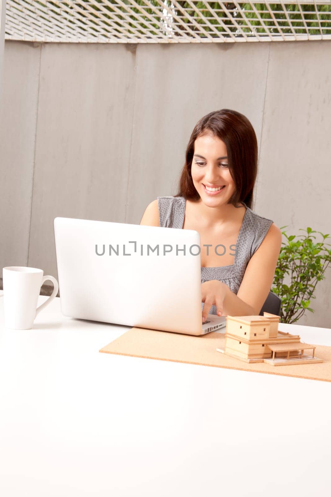 An architect using a laptop computer with a model house on the desk