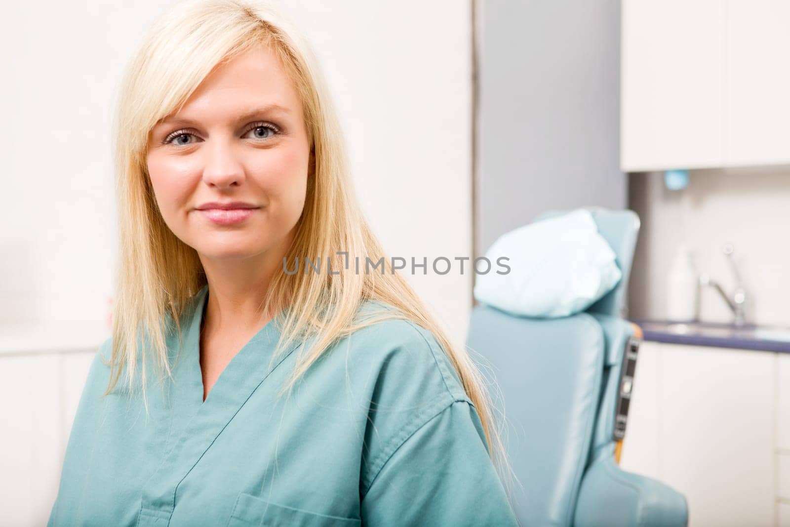 A portrait of a dental hygienist in front of a dental chair