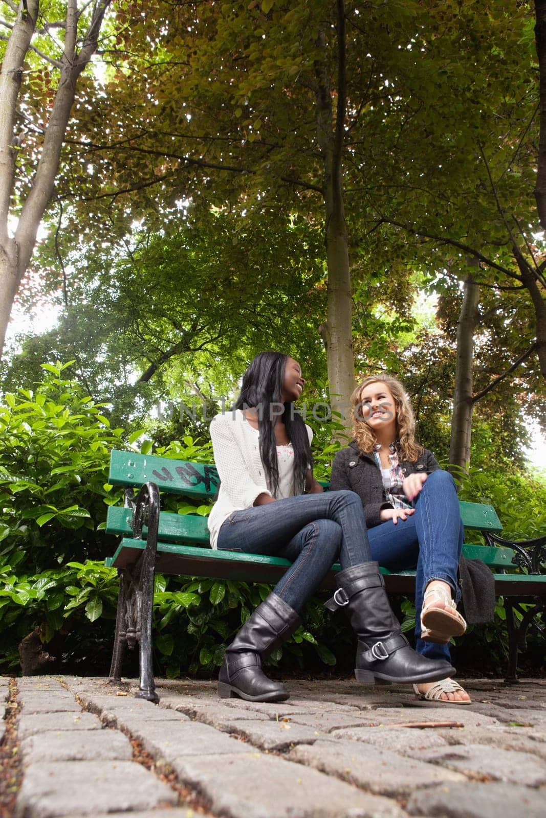 Low angle view of two young relaxed female friends chatting in the park