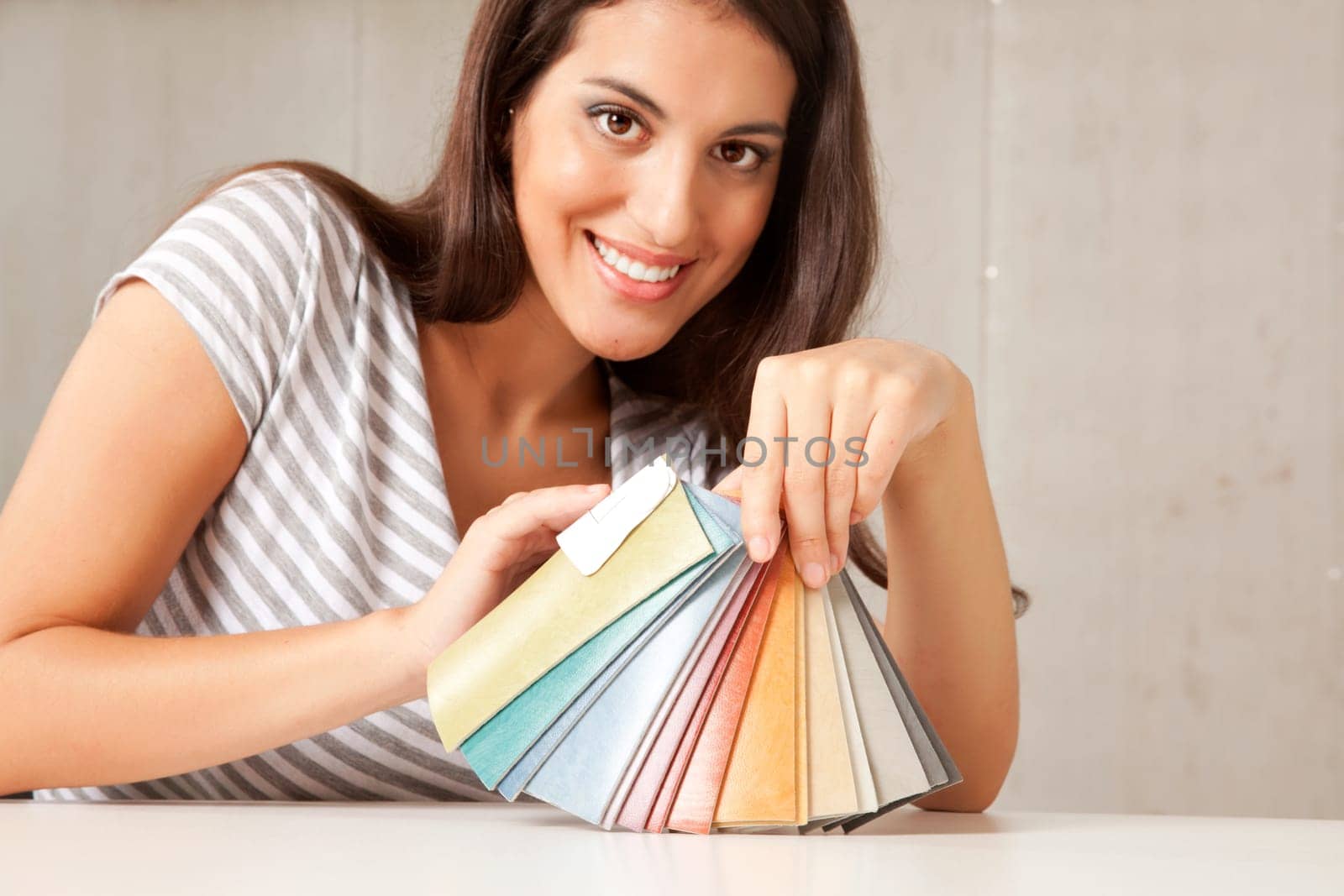 A young female interior designer displaying a group of color swatches.  Sharp focus on swatches