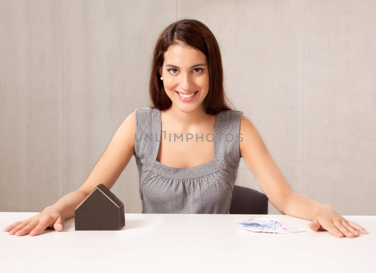 A conceptual housing market shot, a woman with model house and Euro money