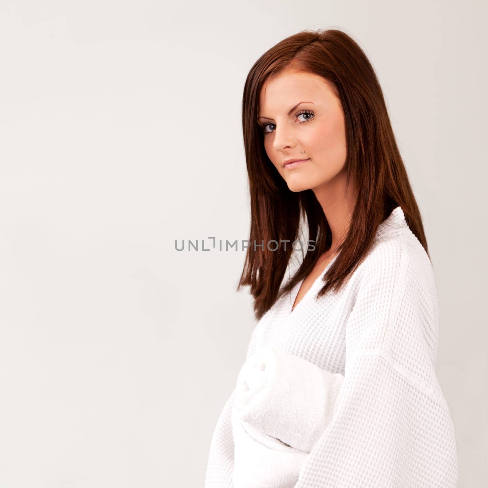 A pretty young woman in a bathrobe isolated on white