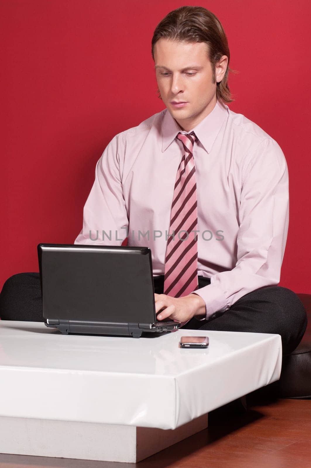 Concentrated businessman using a laptop while sitting on a floor