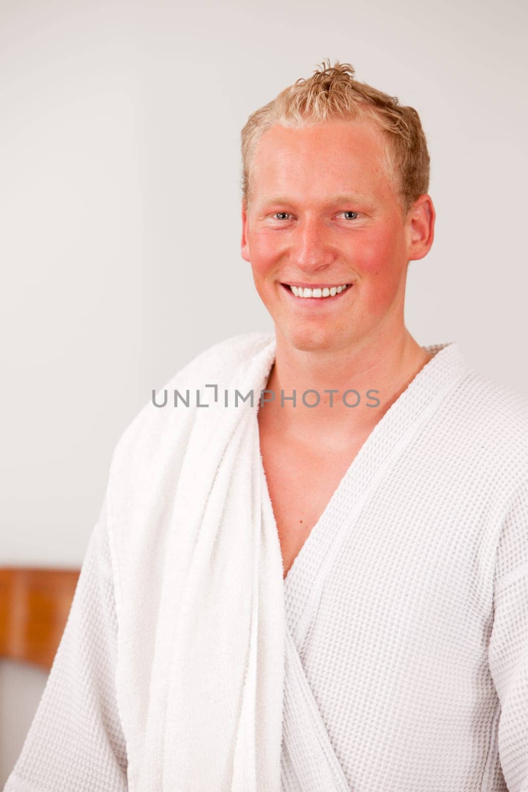 A happy handsome bonde man in a bathrobe smiling and looking at the camera