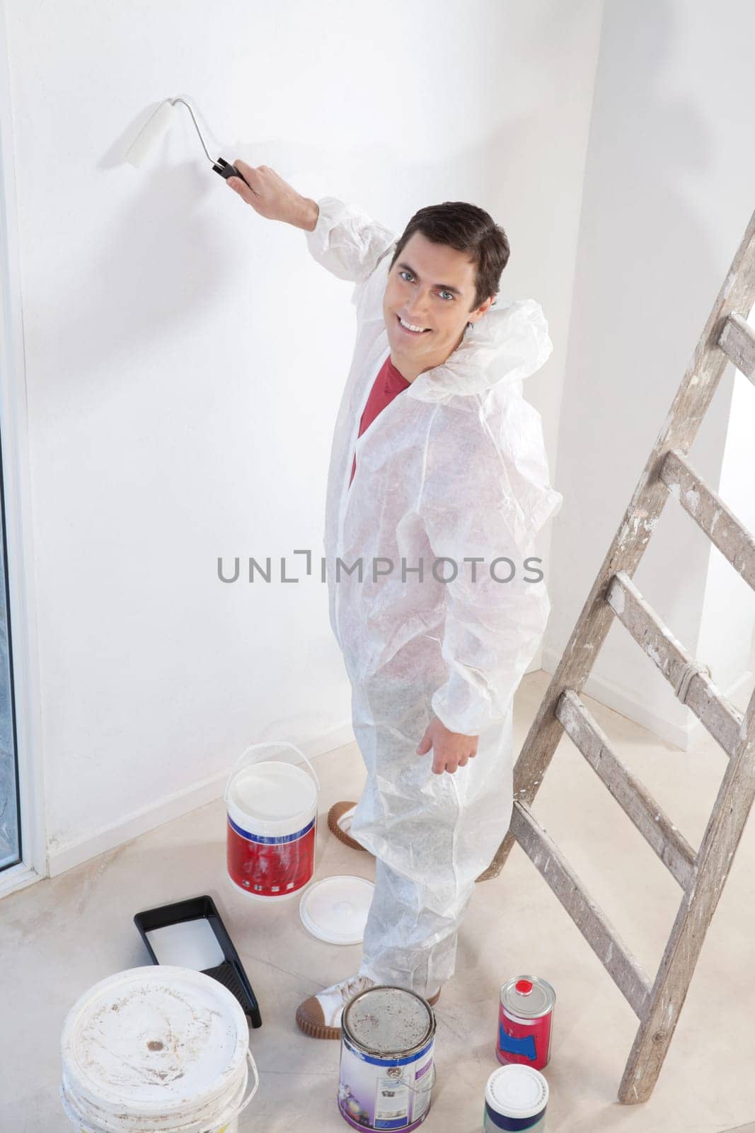 Portrait of an smiling workman painting the wall with a roller