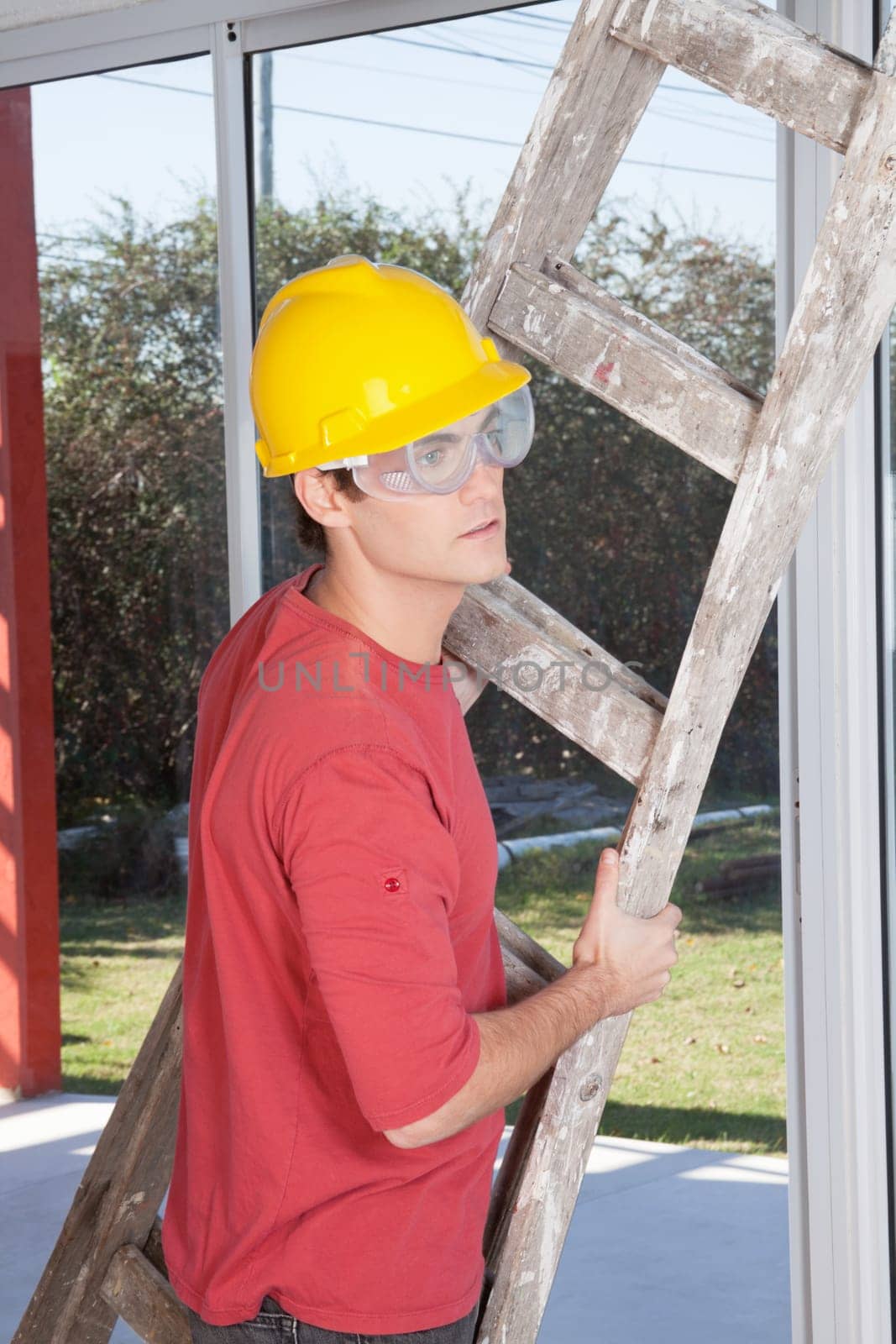 Male construction worker holding ladder in hand