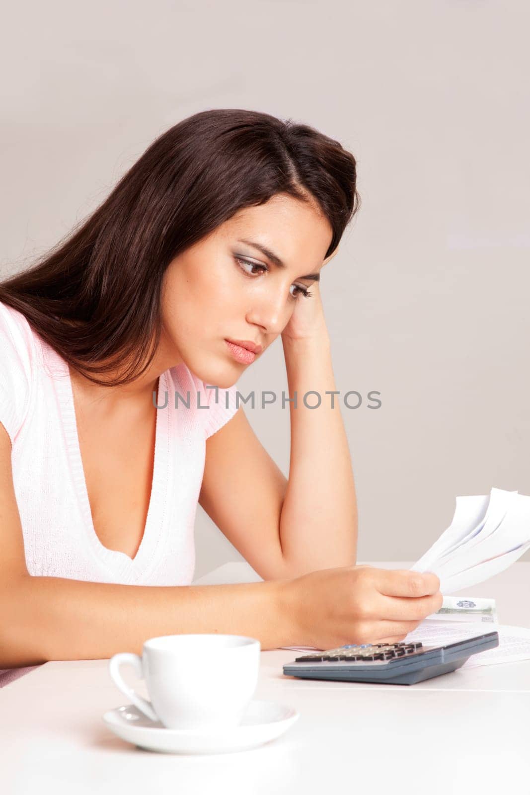 A woman sitting at a desk with calculator and papers planning a budget