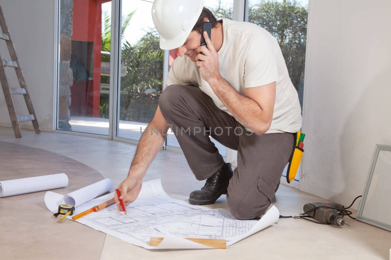 Construction worker working on blueprint and talking on cellphone
