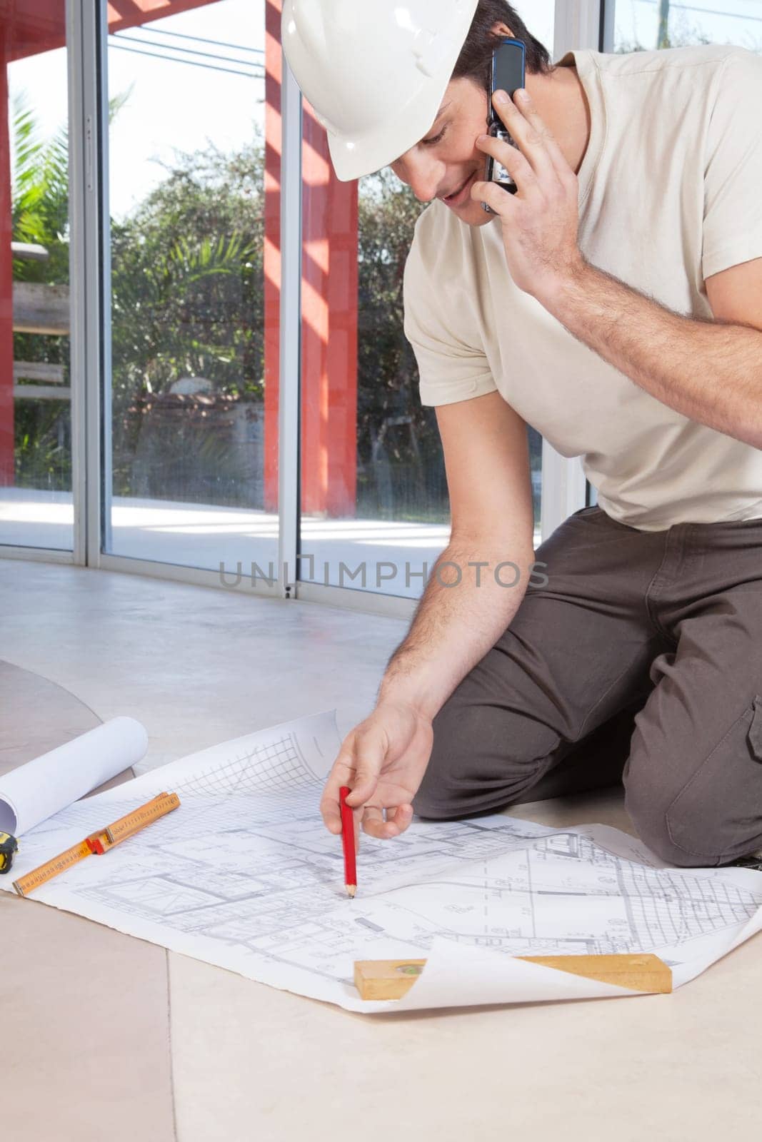 Architect working on blueprint and talking on cellphone