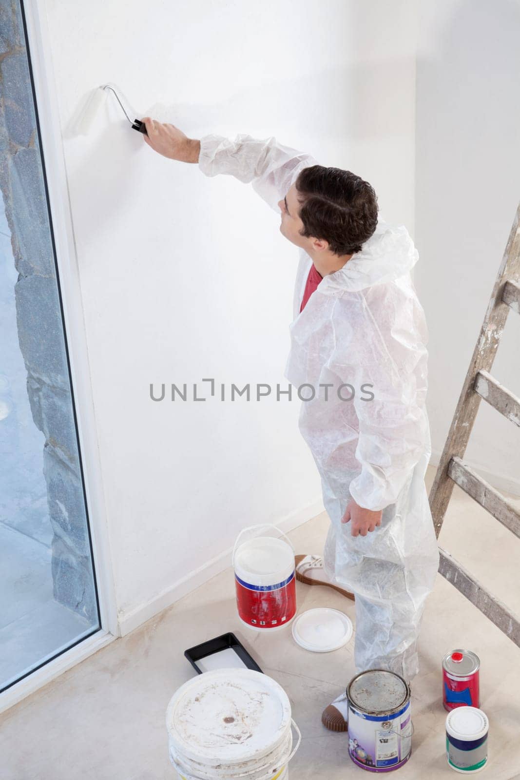 High angle view of workman painting the wall with a roller