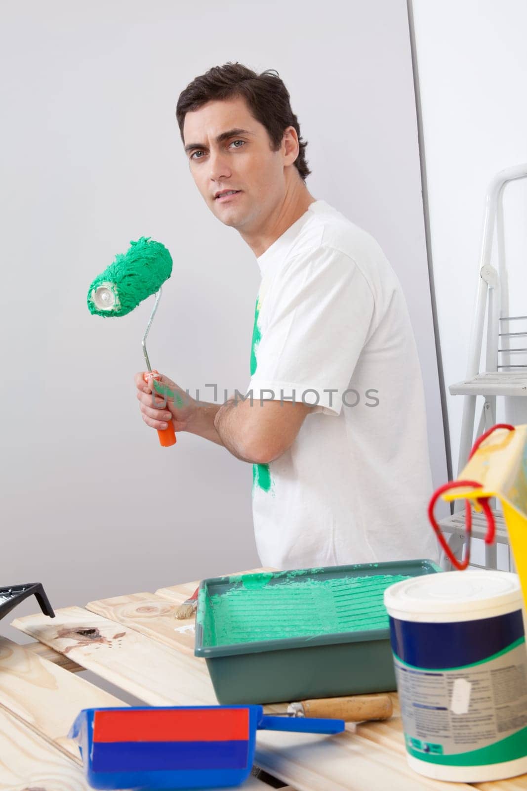 Portrait of casual man holding a roller paint brush in his hand