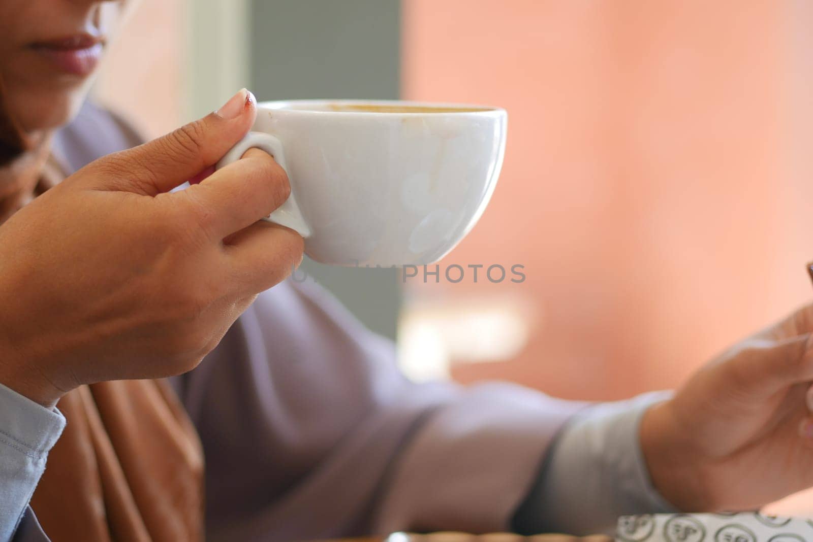 A person savors a hot drink while seated peacefully indoors.