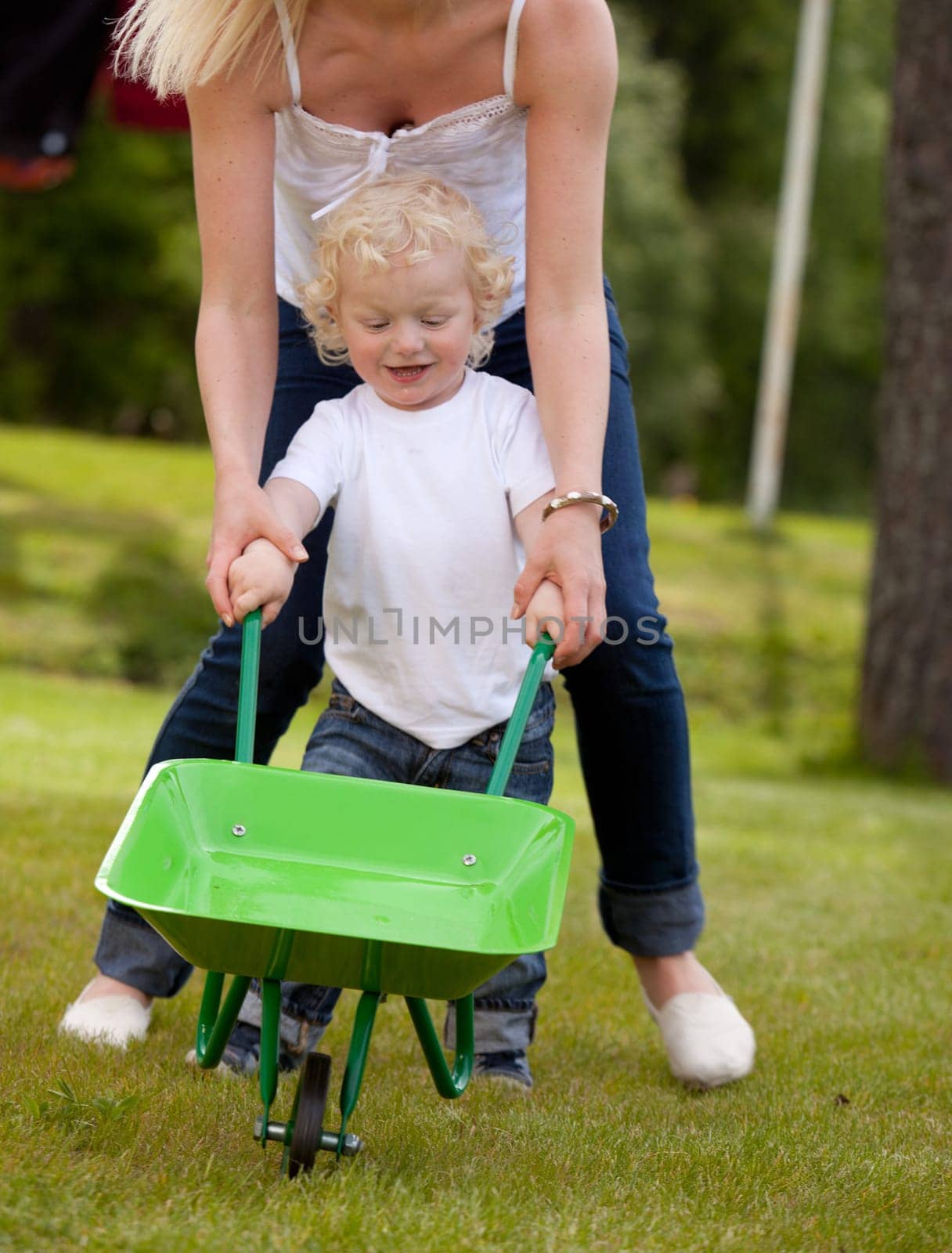 A mother and child playing outdoors with a wheelbarrow