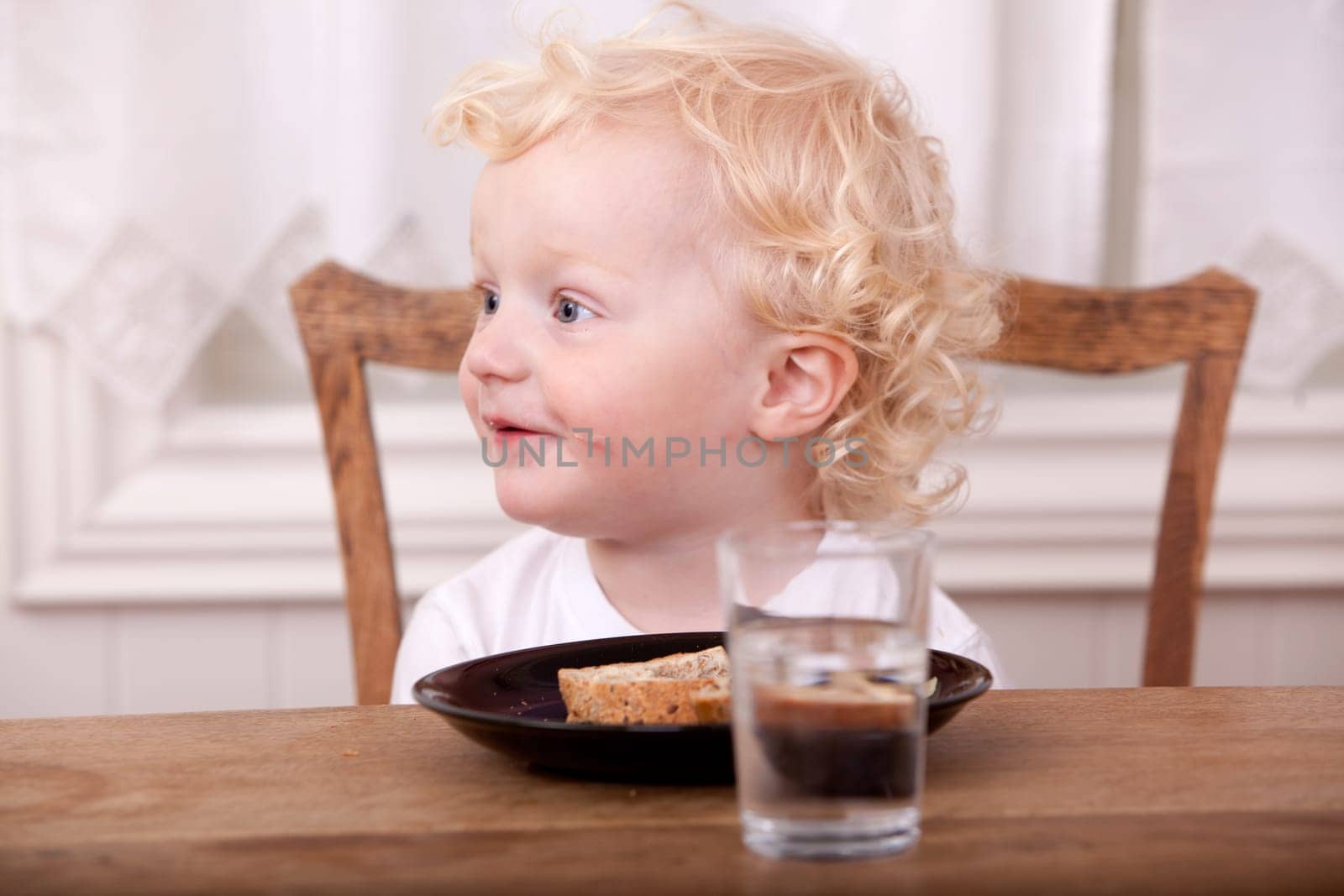 A young boy at the lunch table, looking off camera and smiling