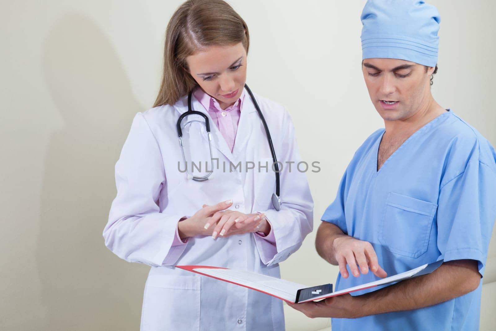 Doctor and nurse reading information from file folder