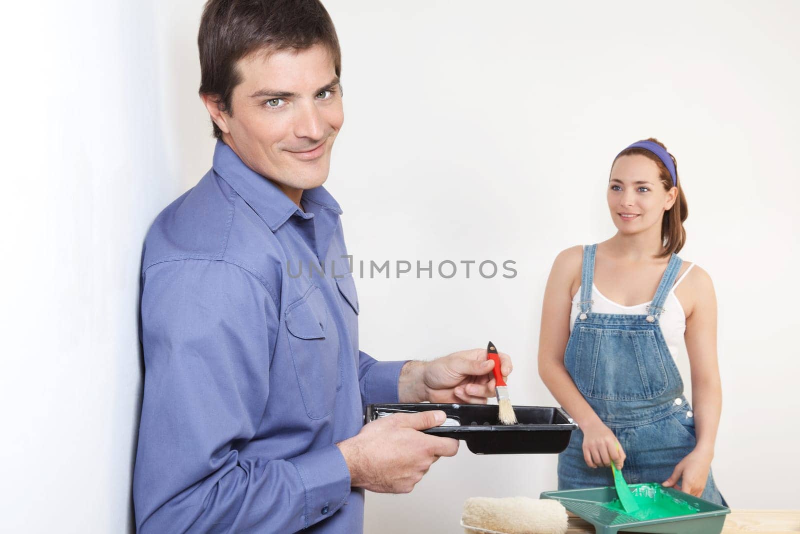 Portrait of young husband mixing paint while wife watching