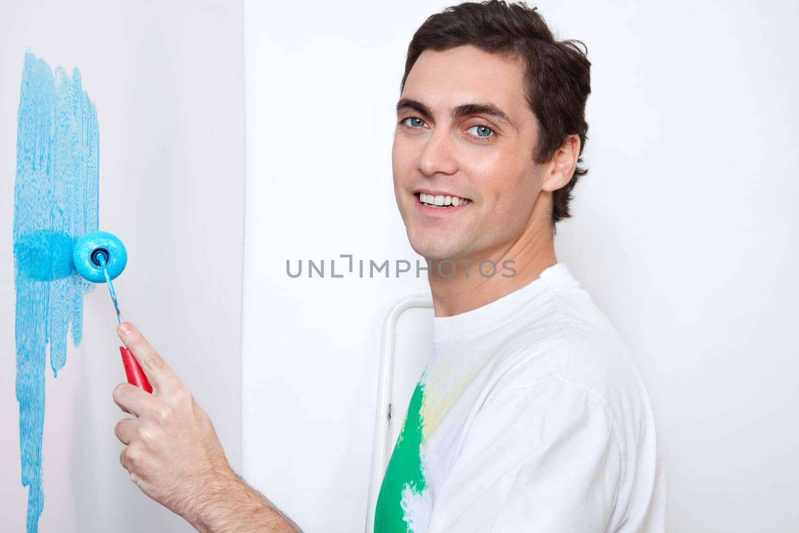 Close-up portrait of happy man painting wall with roller
