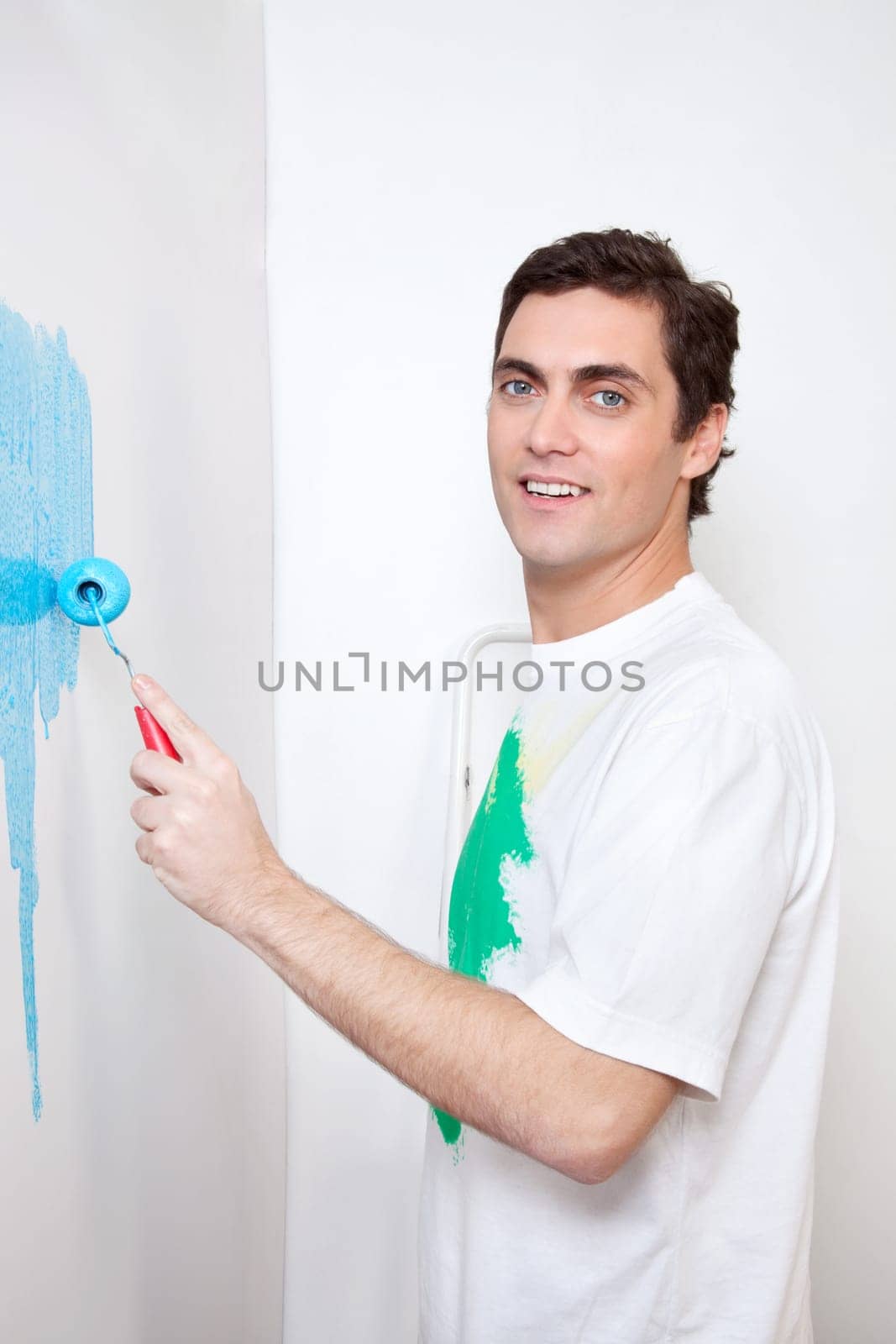 Portrait of smiling man painting his house with roller