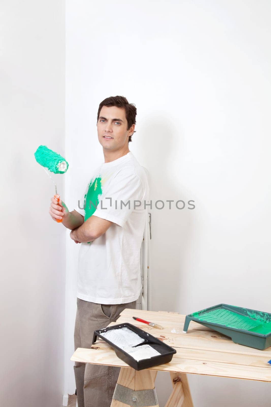 Portrait of man holding paint roller at home