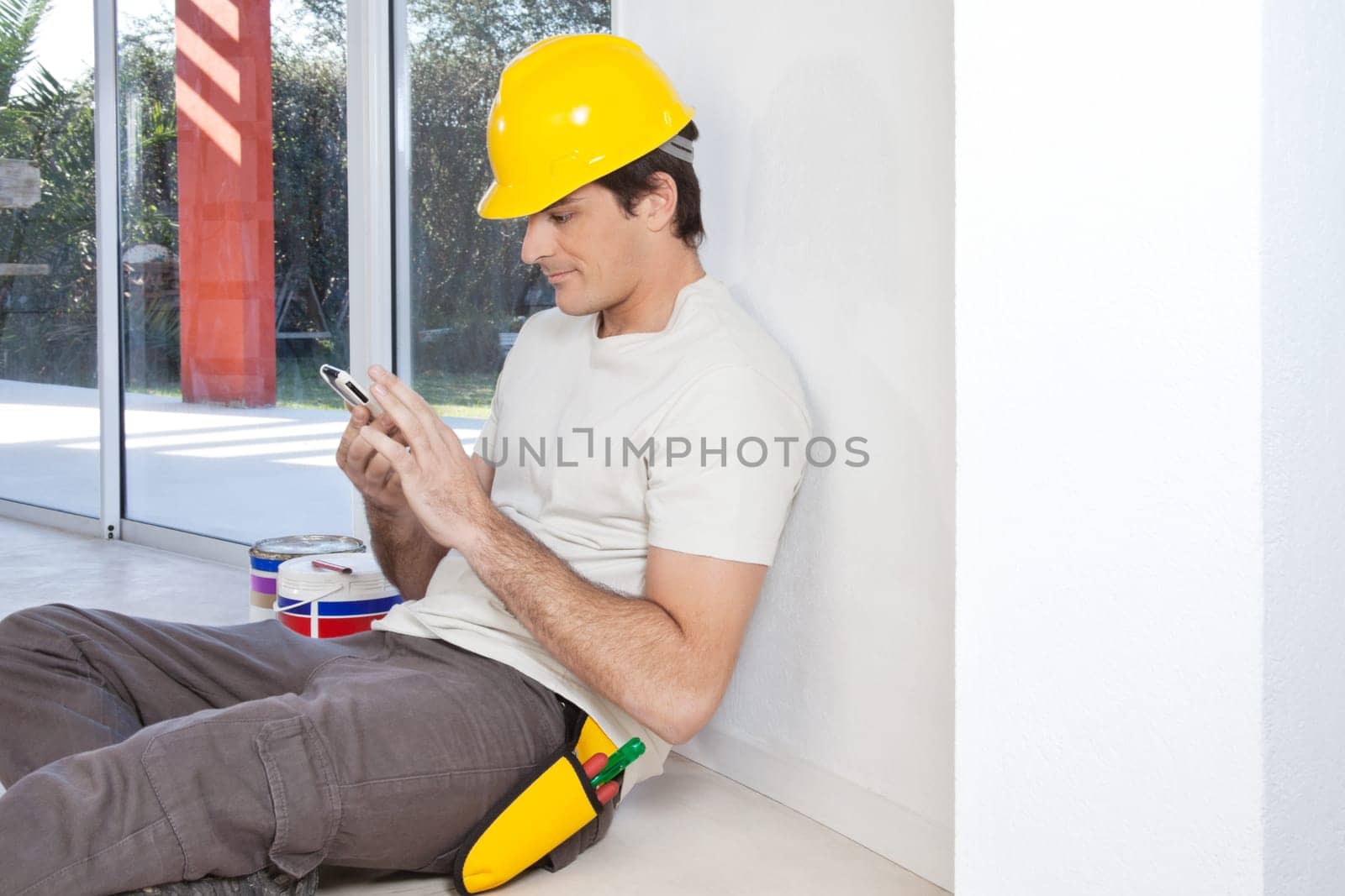 Construction worker looking in cellphone while sitting